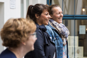 Drei weiße Frauen in lockerer Reihe in Präsentationsstellung. Draußen, nahe Häuserwand.